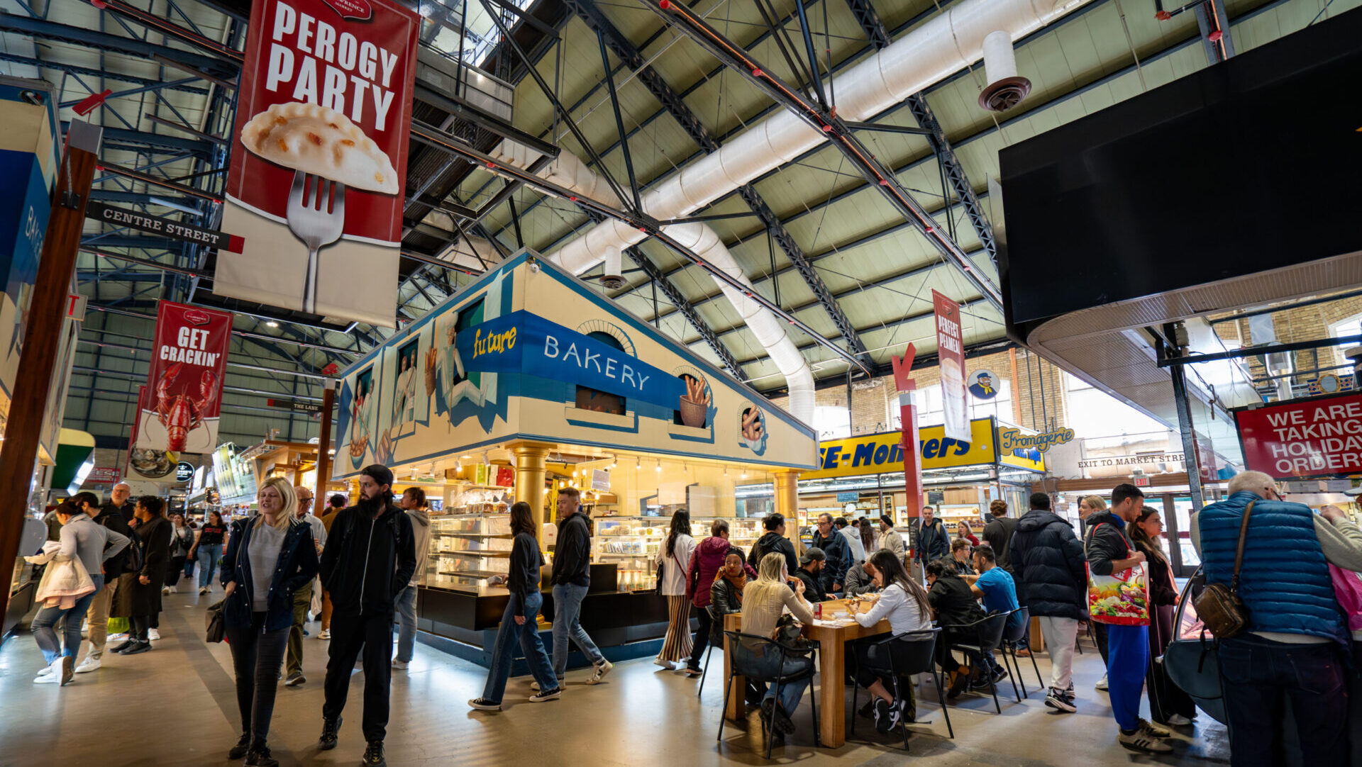 A bustling scene of shoppers exploring stalls at St. Lawrence Market, a prominent public market in Toronto.