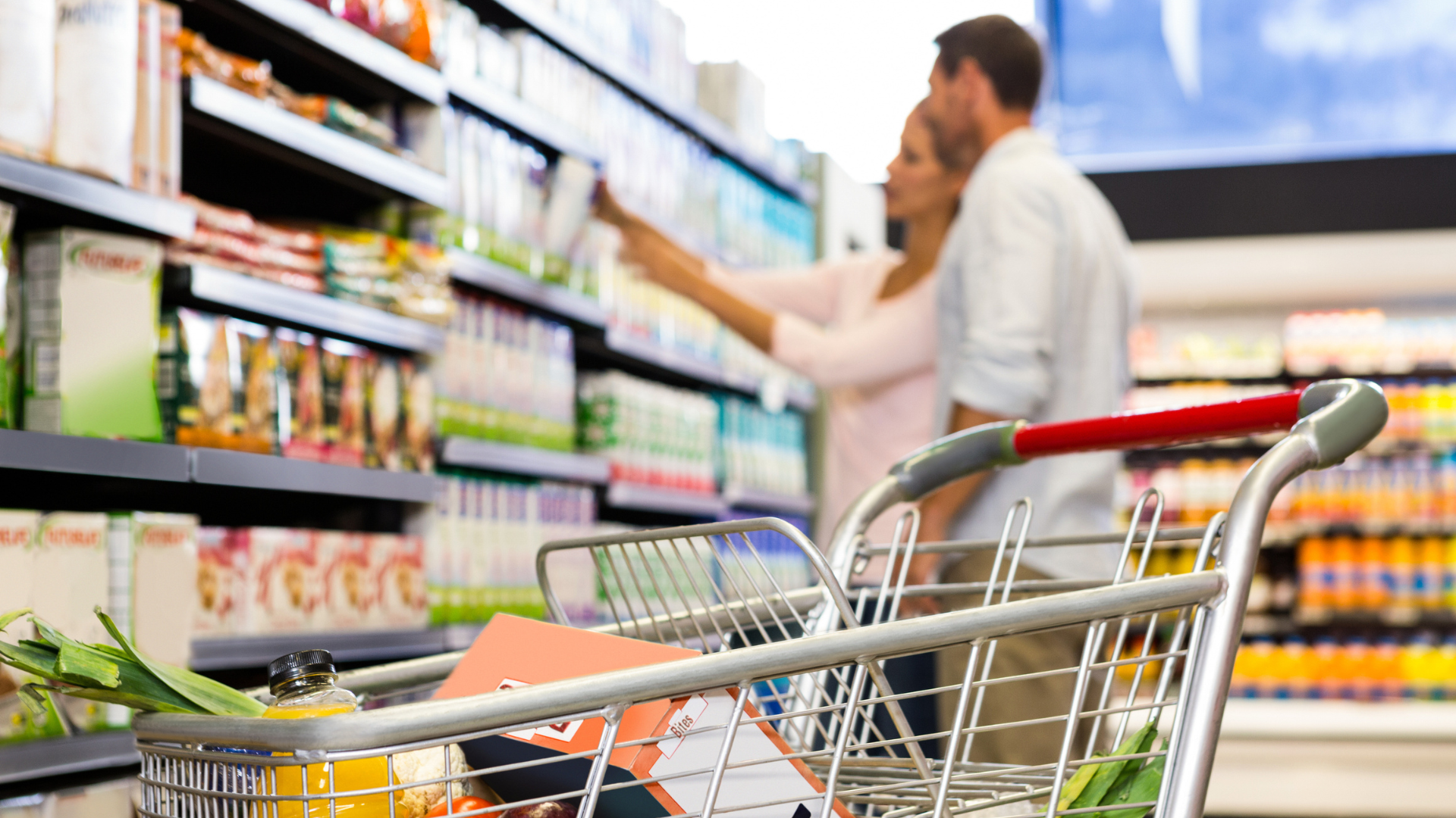 A man and woman are shopping together in a grocery store, browsing through various products on display.