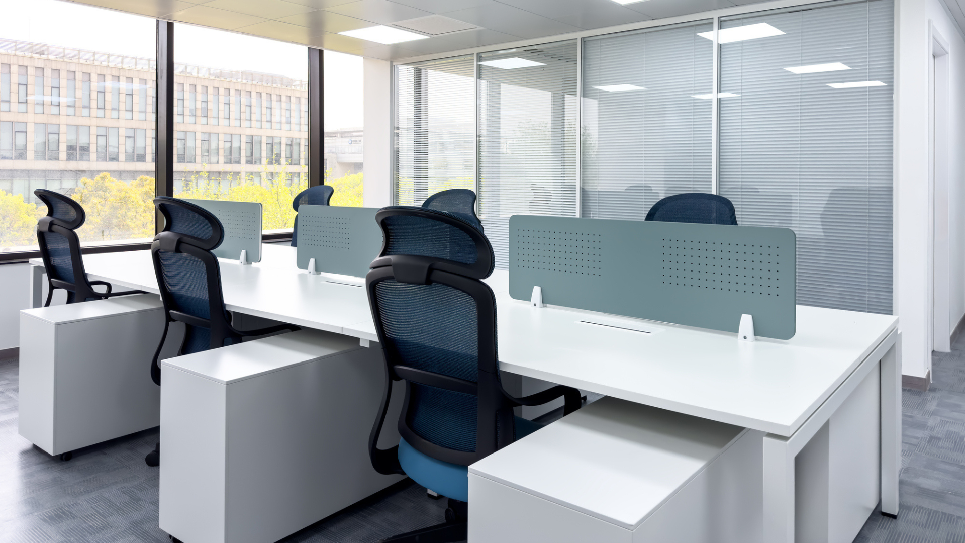 An empty office space showcasing white desks and chairs.