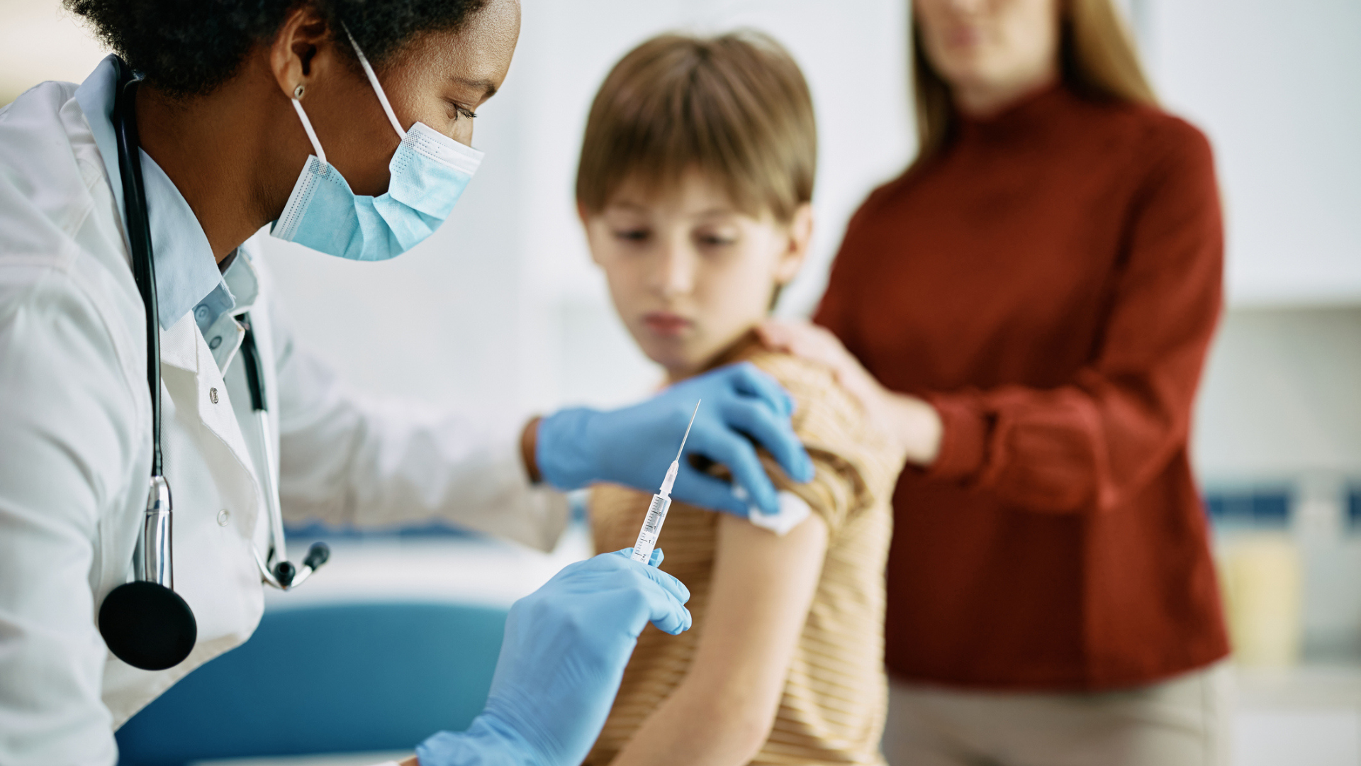 A healthcare professional administers an injection to a child in a doctor's office.