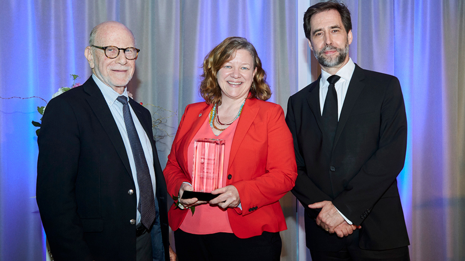 Meredith Low smiles with the DeGroote Dean and The Directors College director, proudly holding her 2019 Gil Bennett Gold Standard Award.