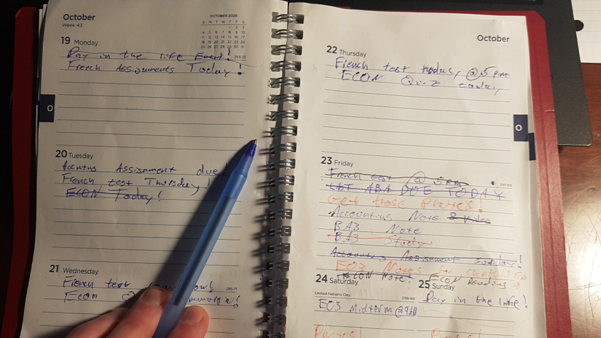 A person writes in an open agenda notebook, holding a pen, capturing thoughts and plans on the page.