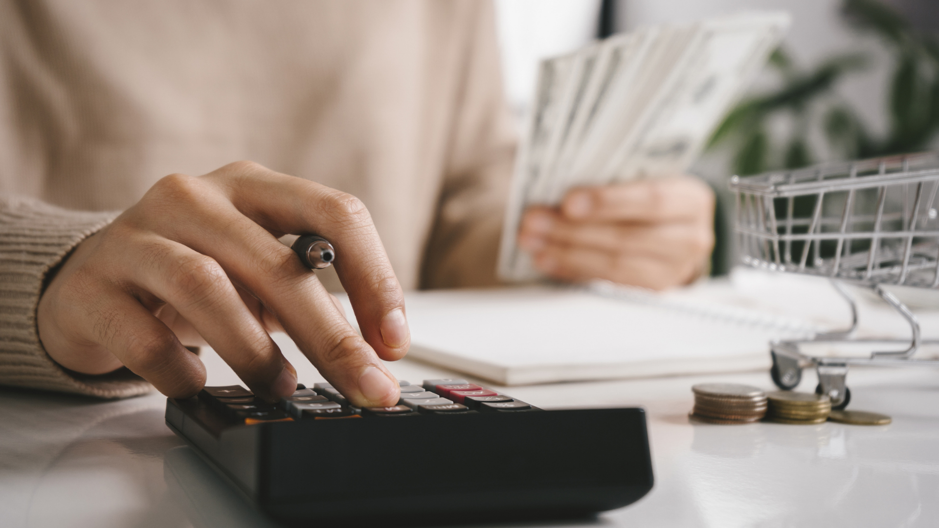 Close-up of a person calculating expenses with a calculator and cash, focusing on budgeting to save money on food costs.