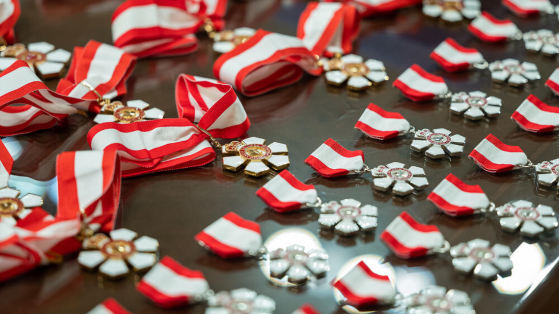 A table adorned with numerous red and white ribbons medals, showcasing the Order of Canada medals elegantly arranged.