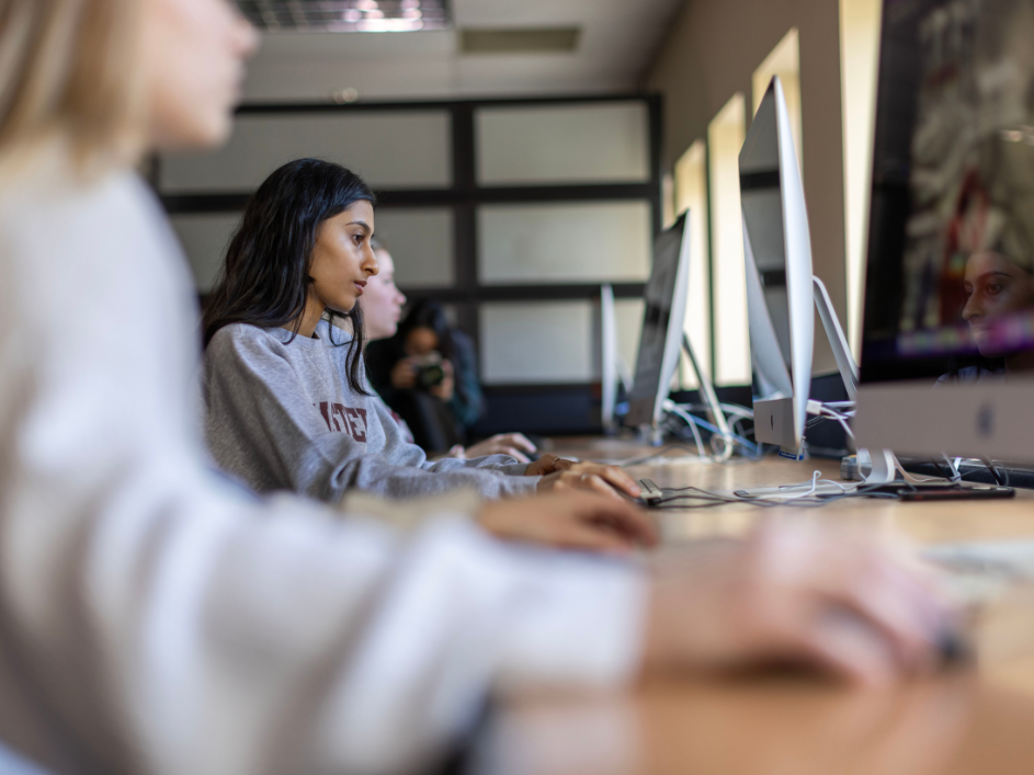 A row of DeGroote students focused on their computers in a classroom setting.