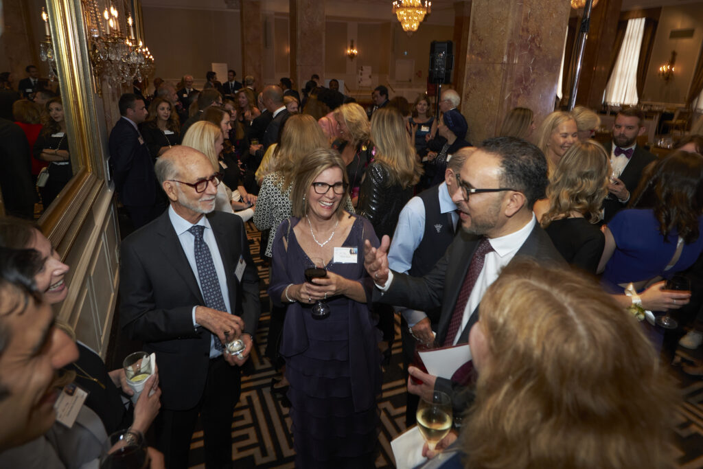 A business event scene featuring Dean Khaled Hassanein discussing with attendees at the Accolades reception.