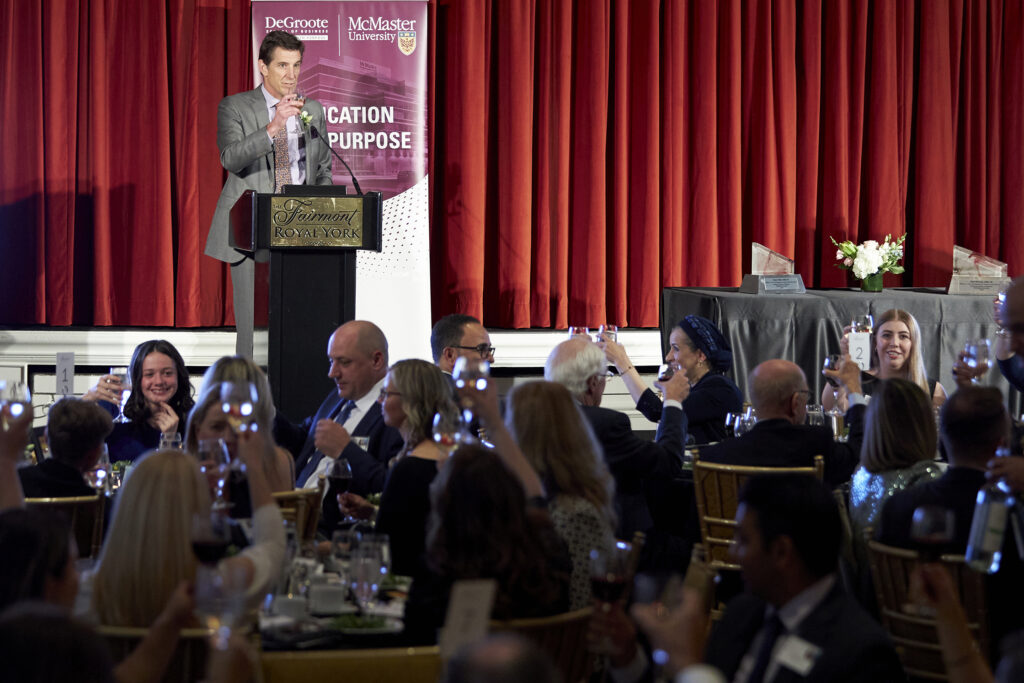 Quentin Broad speaks at a dinner, addressing attendees with enthusiasm and charisma during his presentation.