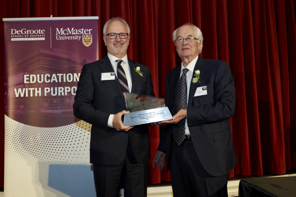 Paul McLean and Wayne C. Fox in suits, proudly holding an award together, showcasing their achievement and camaraderie.