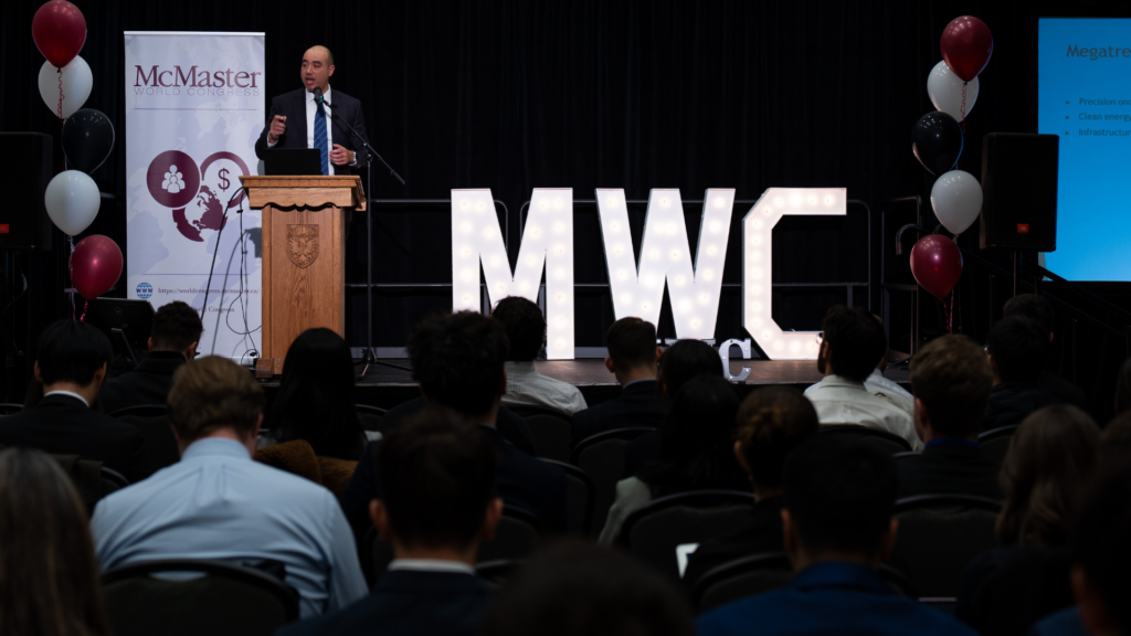 Paul Lee Chin, delivering a speech, with large MWC signage visible to his right.