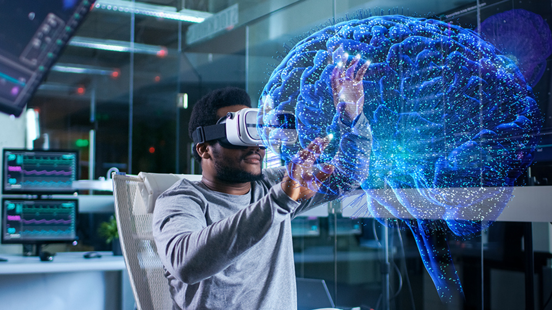 A man wearing a virtual reality headset engages with a computer screen, immersed in a digital experience.