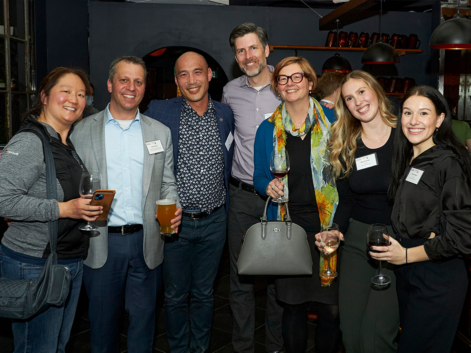 A group of DeGroote alumni warmly smiling at a lively networking event.