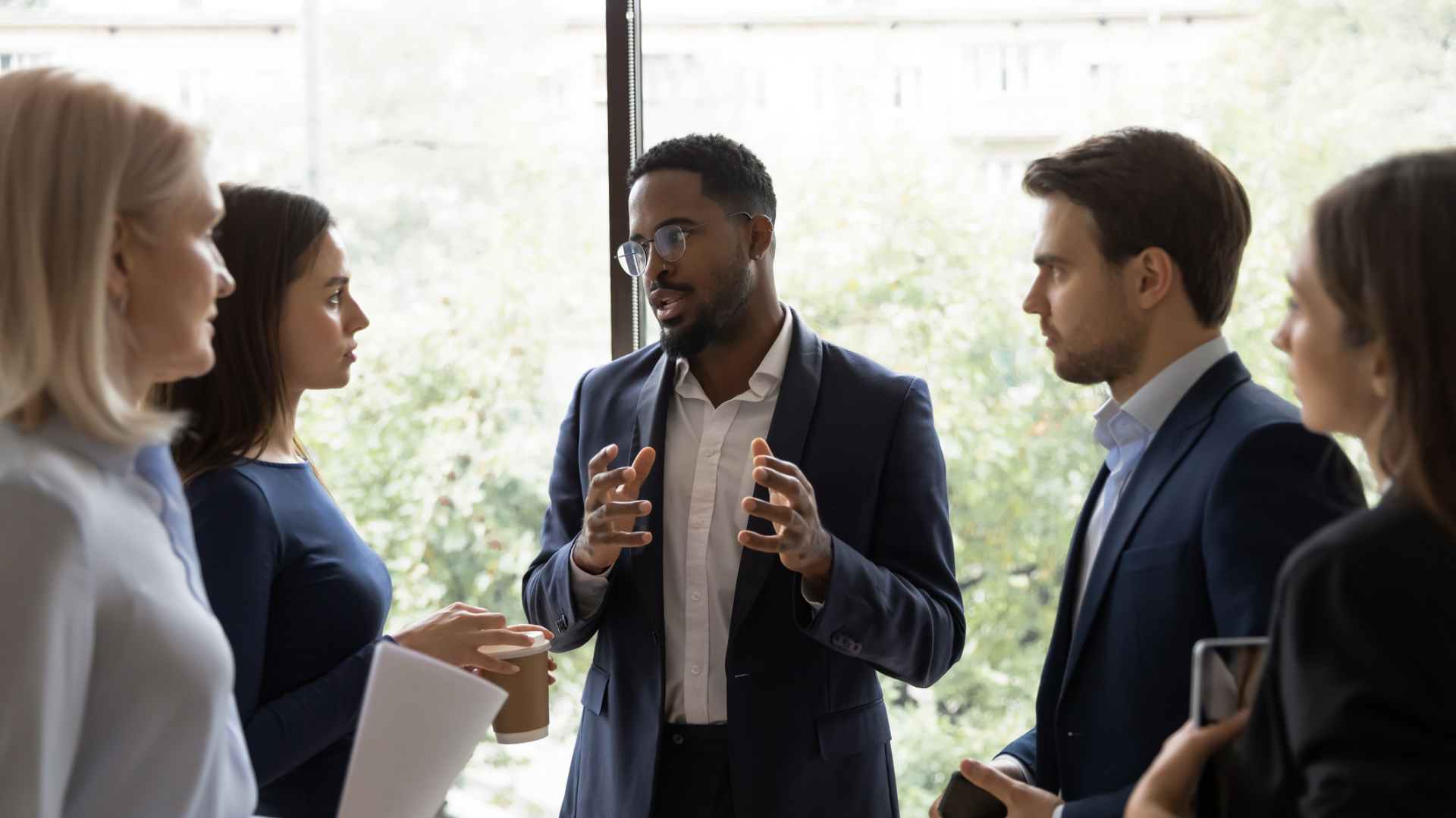 A group of business professionals engaged in a discussion within a modern office environment.