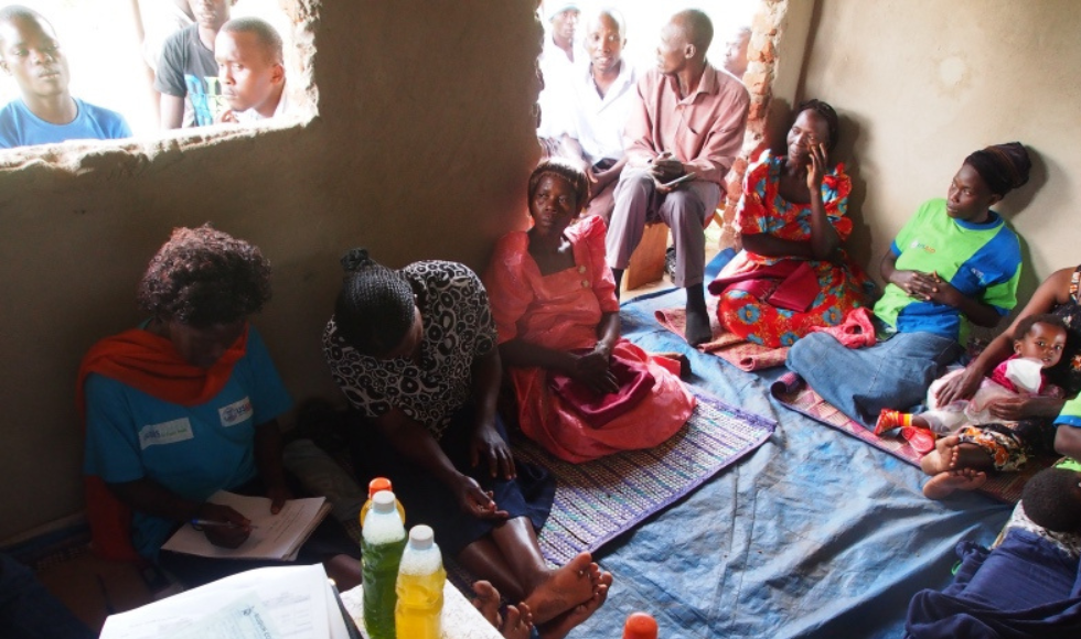 A group of female Kenyan entrepreneurs seated on the floor, engaged in discussions and note-taking for their soap-making business.