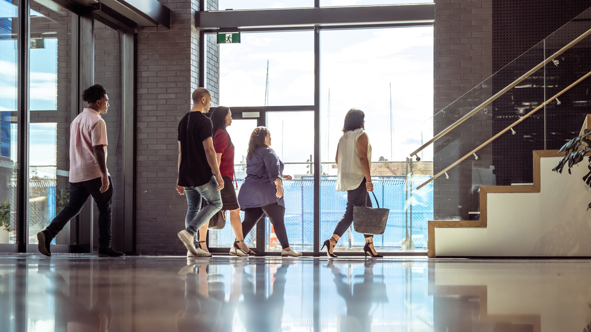 A diverse group of people strolling through a hallway, symbolizing a return to the office environment.