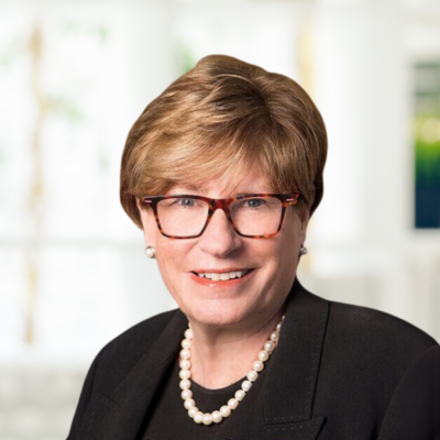 Karen Maidment, wearing glasses and a necklace, smiles.