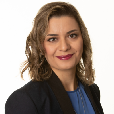 Maryam Ghasemaghaei, smiling, poses for a photo in a blue shirt and jacket.