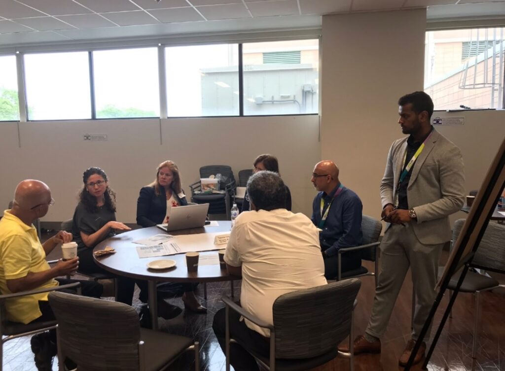 A group of business professionals collaborates around a table, each using laptops and papers for discussion and planning.