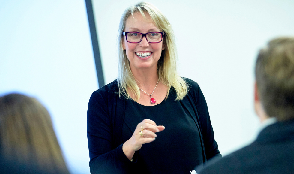 Milena Head, wearing glasses, delivers a presentation to an attentive group.