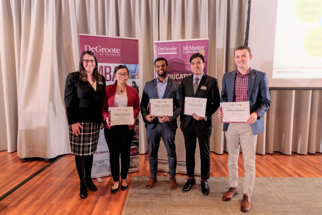 Five nominees for "Co-op Student of the Year" stand in a banquet hall, smiling and holding their certificates in front of a screen.