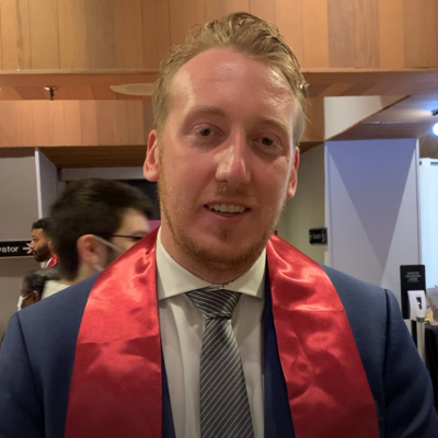 Taylor White, smiling in a suit and tie.