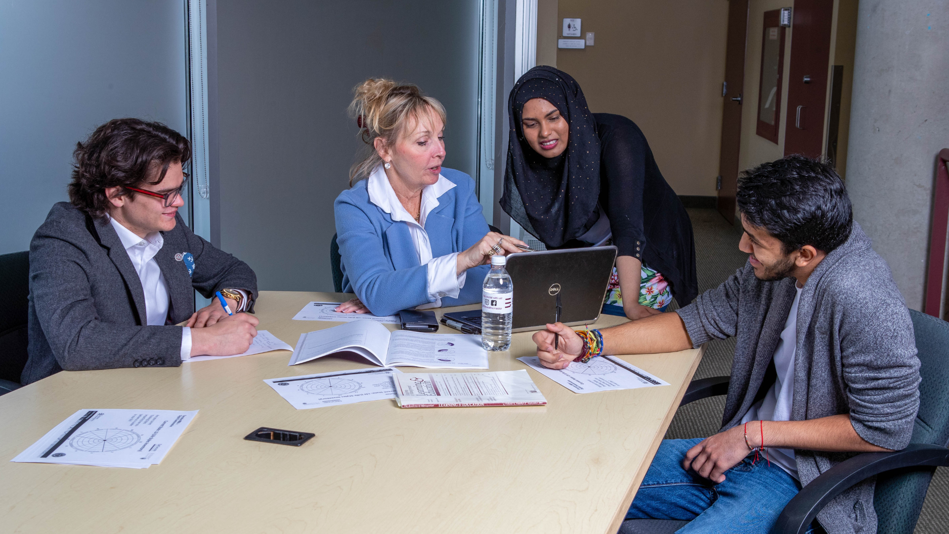 Teal McAteer engages students at a table, highlighting information on her laptop