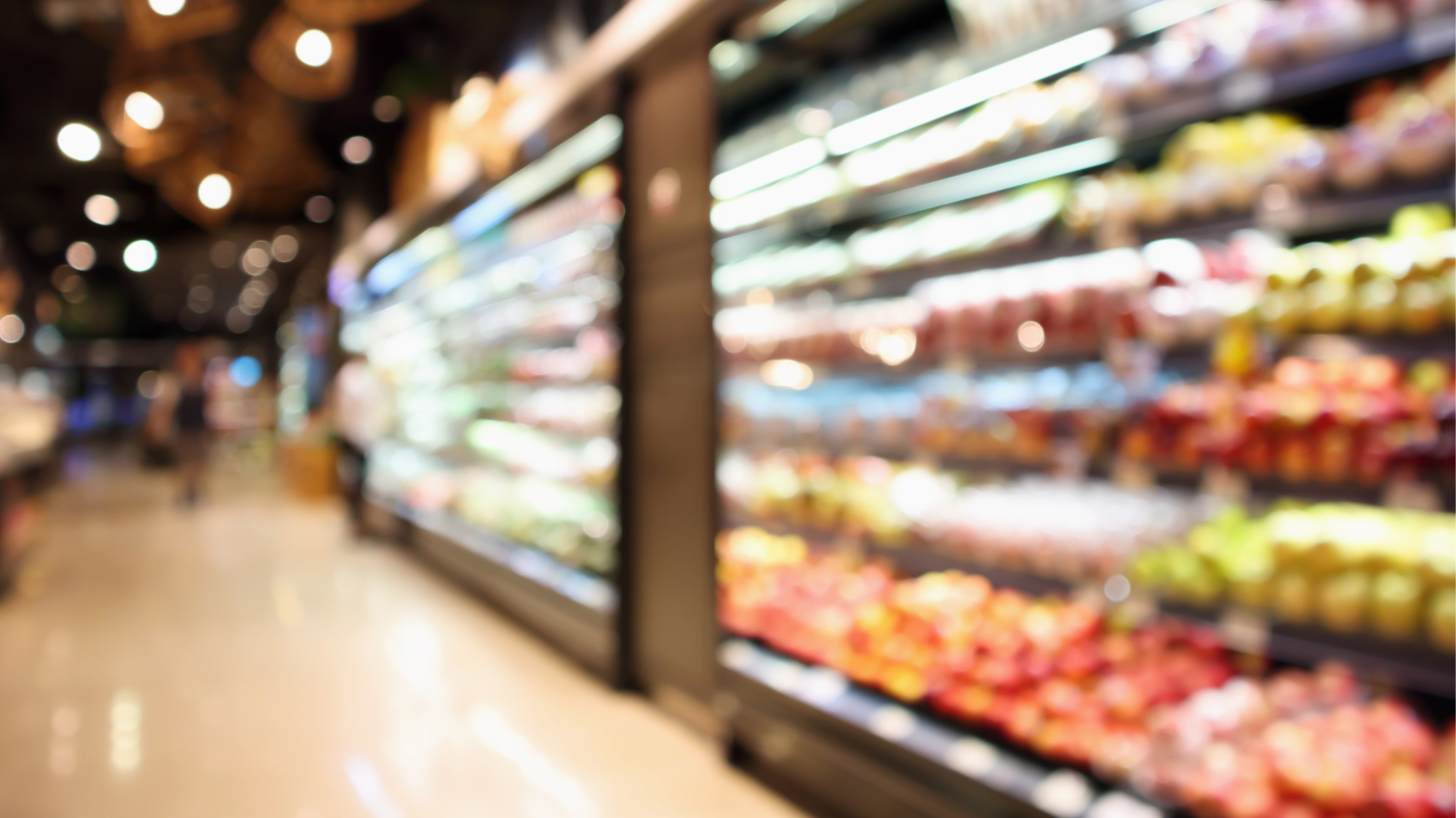 Hazy view of a grocery store's produce aisle, showcasing various fruits and vegetables on the shelves.