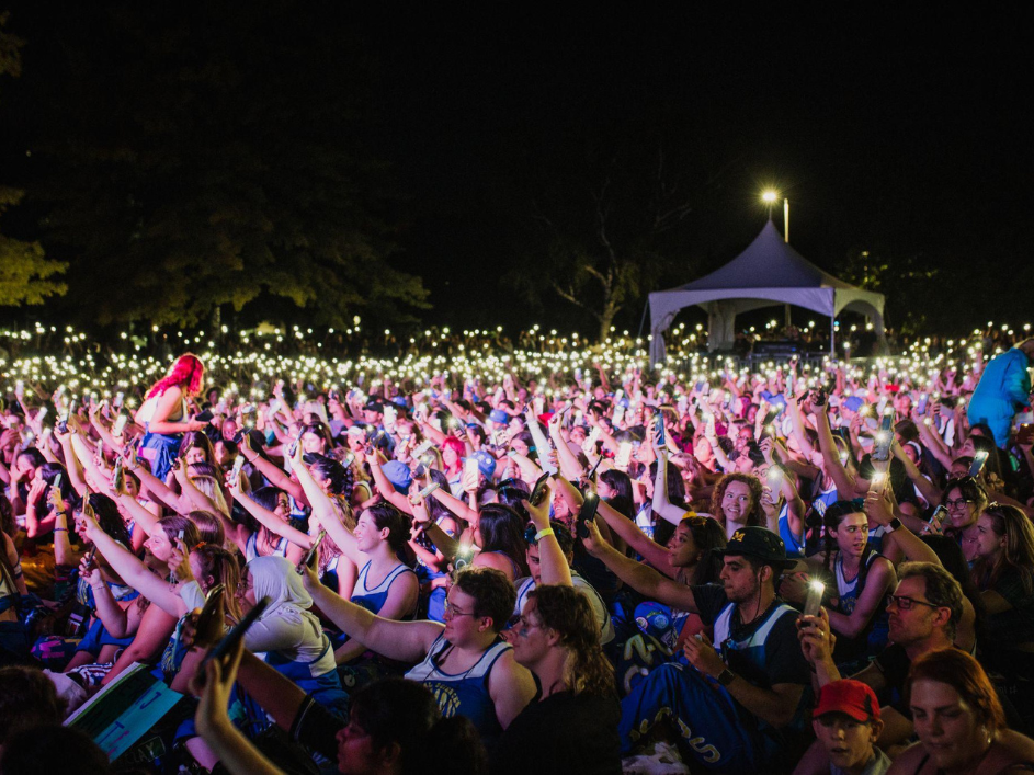 Excited crowd of DeGroote students with hands in the air. Students celebrating at a concert for Welcome Week on campus in Hamilton.