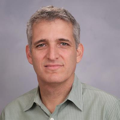 Yair Berson, a man with grey hair, smiles while dressed in a green shirt.