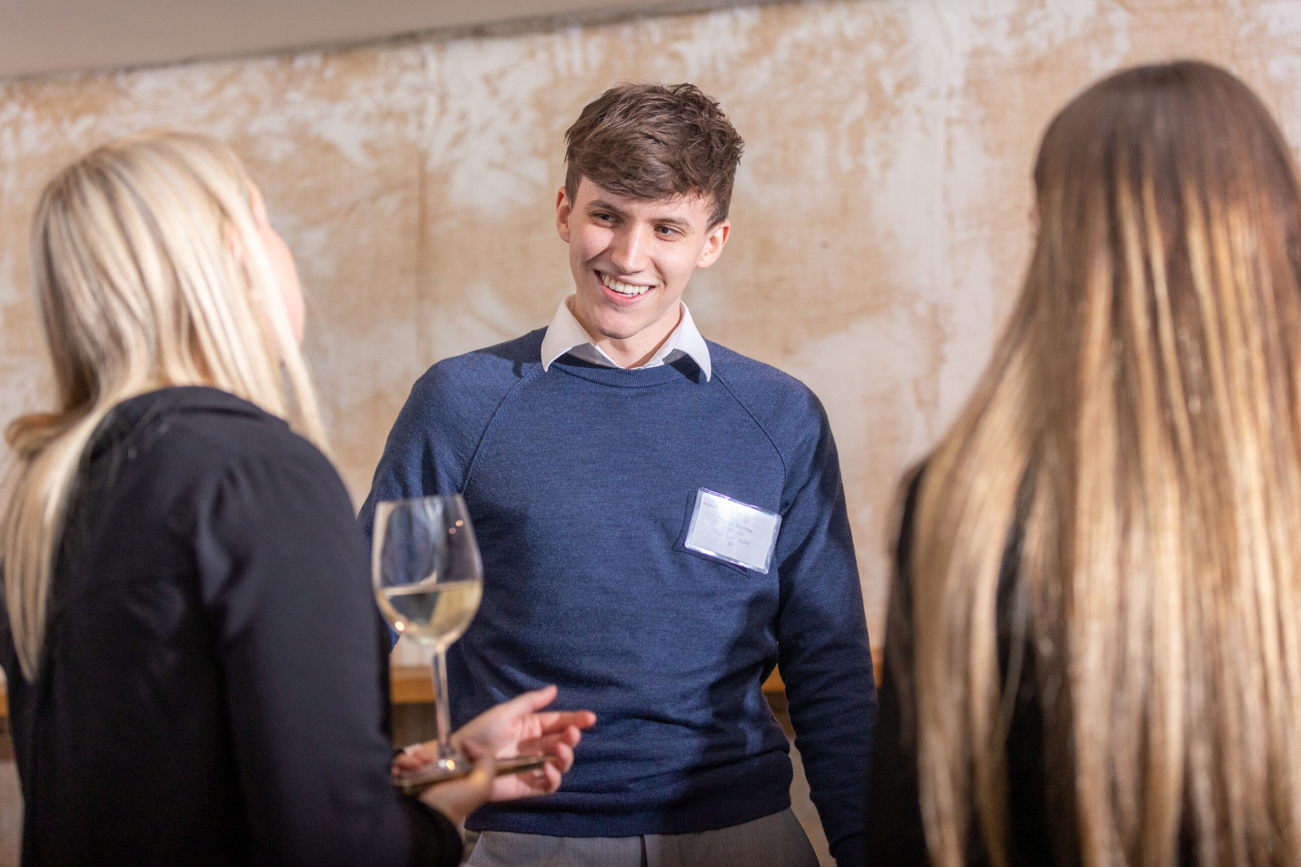 A man engages in conversation with two women at a networking event, fostering professional connections among them.