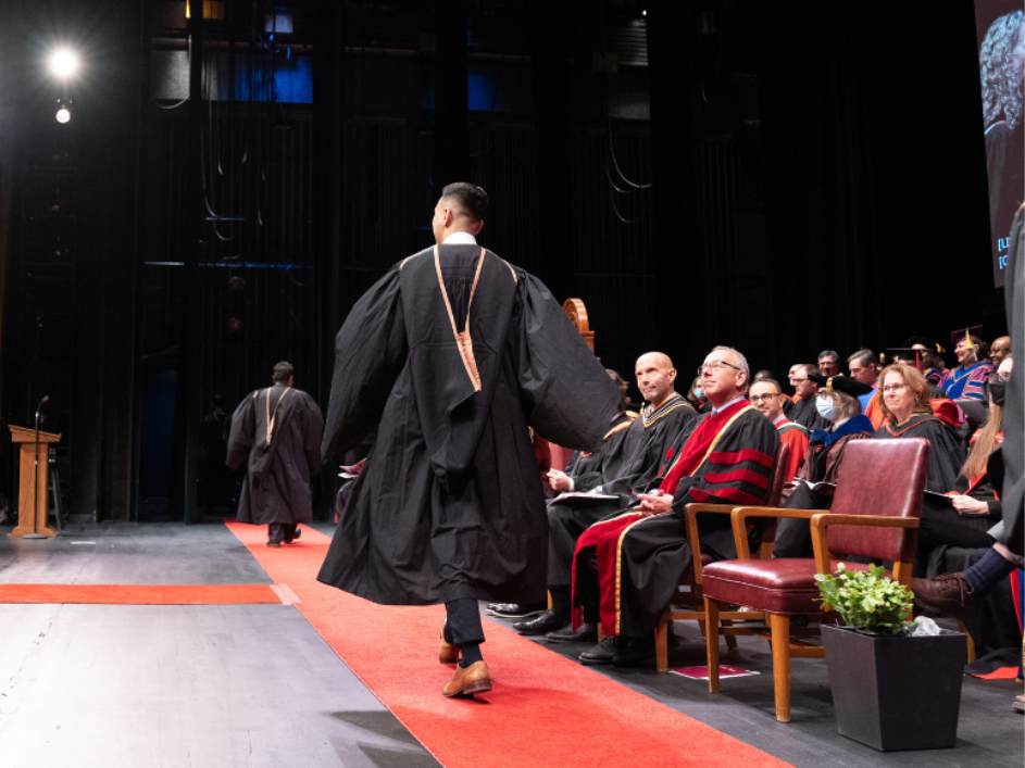 Graduate walking across stage for fall convocation at McMaster.