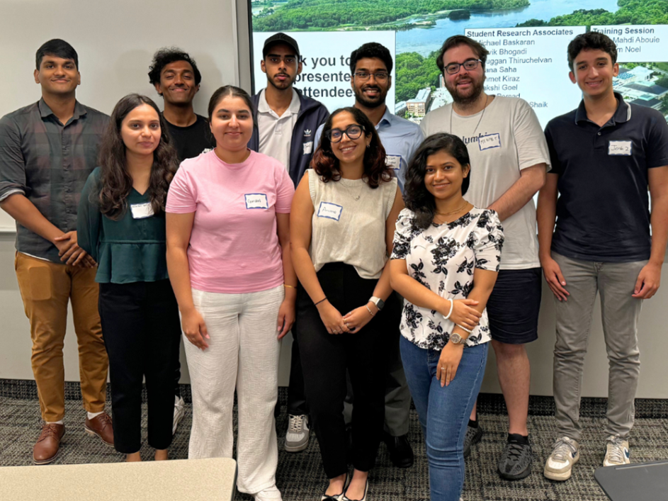 A group of student researchers smiles for a photo in front of a projector screen.