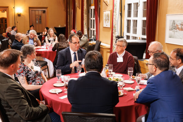 A group of DeGroote researchers engaged in discussion while seated around a dining table.