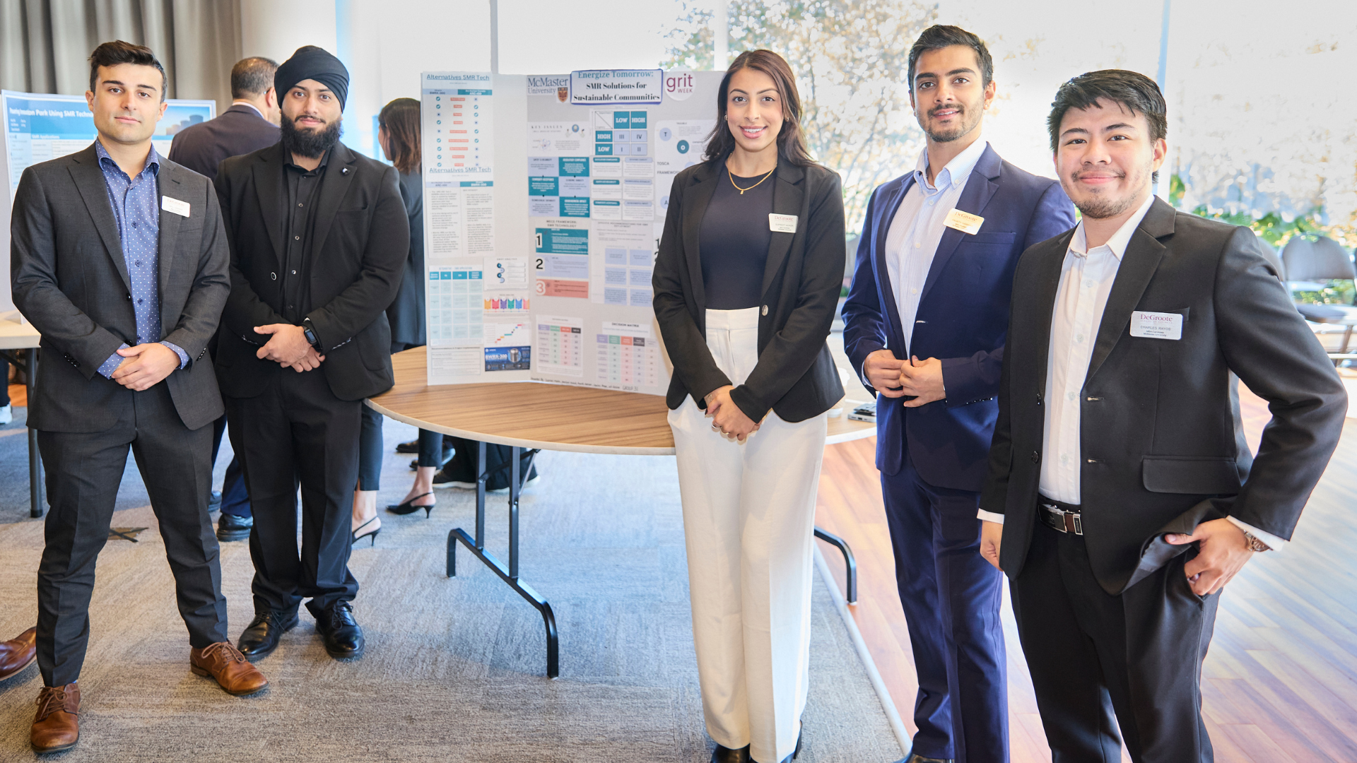 MBA students in front of their posters, presenting their work.