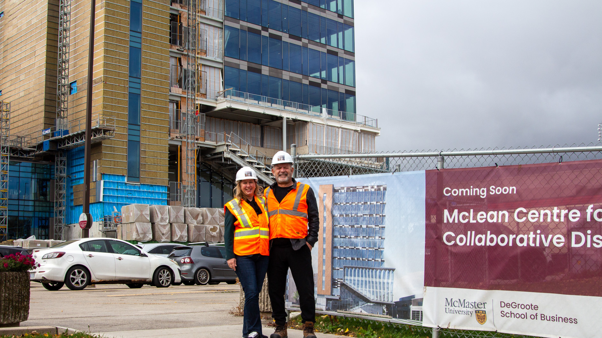 John Marinucci and Sarah Vienot, wearing safety gear, pose in front of the McLean Centre for Collaborative Discovery construction site.