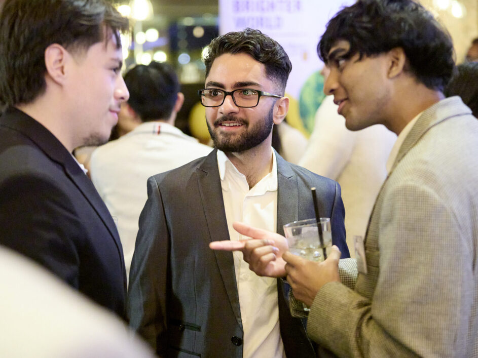 Three men engaged in conversation at a networking event.