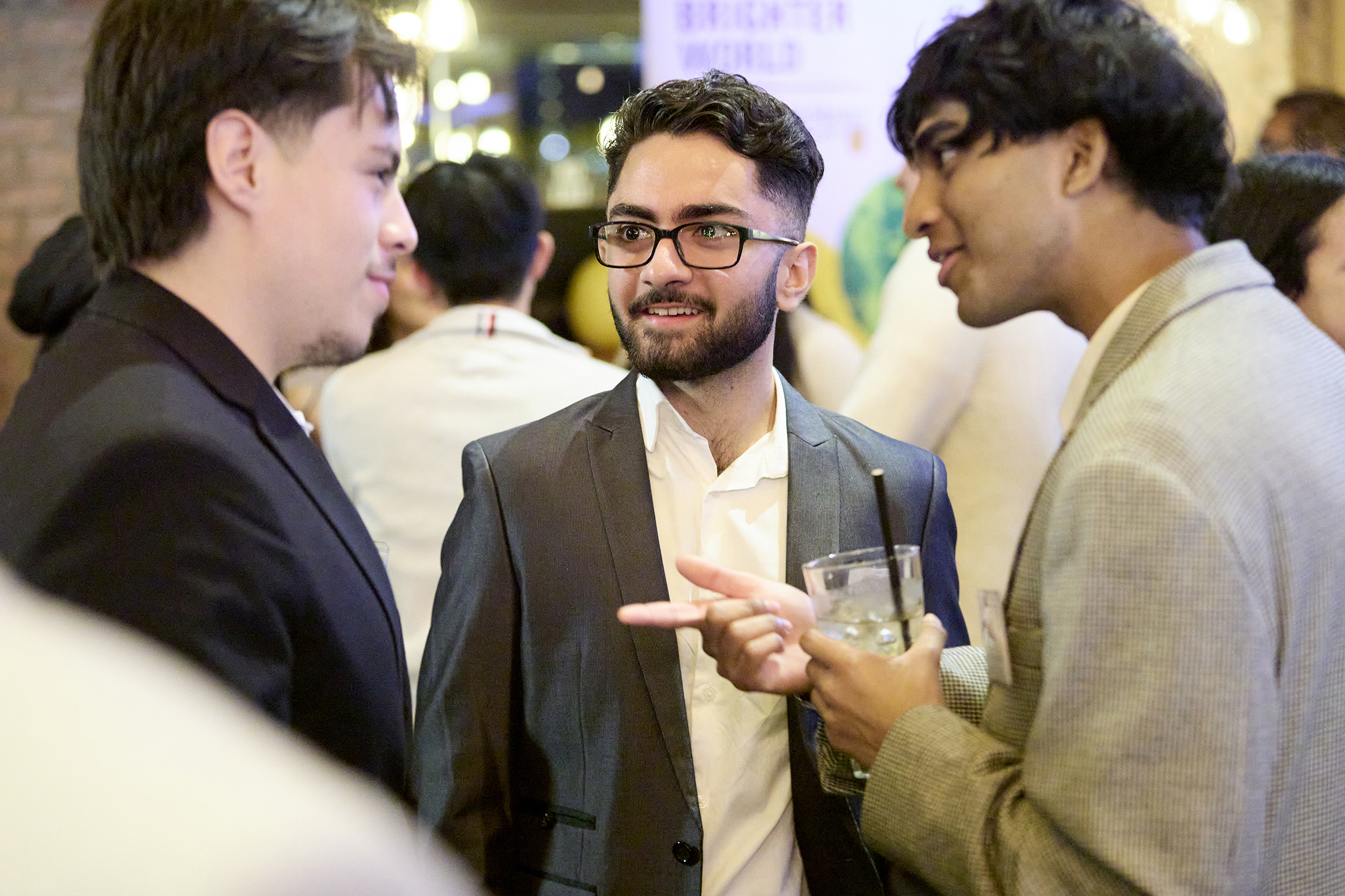 Three men engaged in conversation at a networking event.