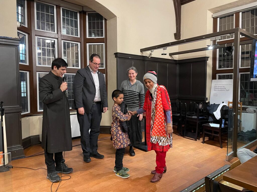 A child who is speaking on stage, with four people listening nearby.