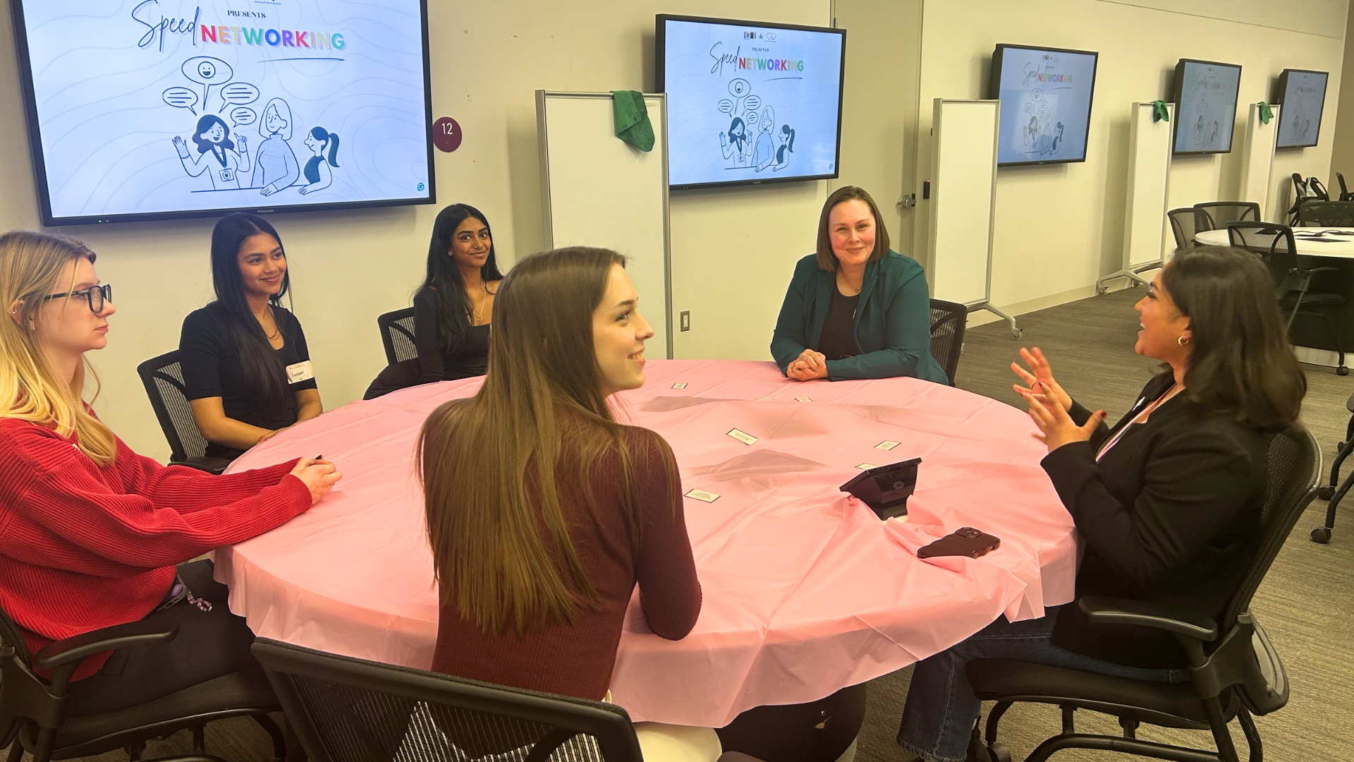 A diverse group of women engaged in discussion around a table.