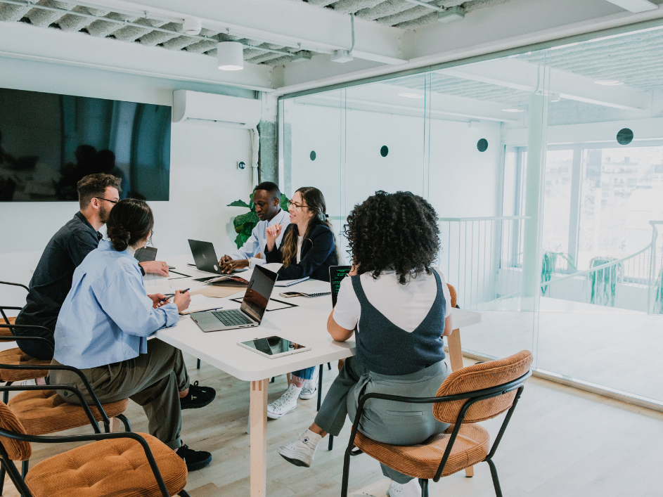 A group of working professionals in a meeting room discussing business topics and solutions.