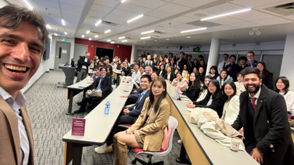 DeGroote professor Amir Akbari smiles with students and judges at the MFin valuation presentation