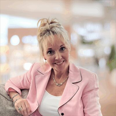 Headshot of Teal McAteer, a smiling woman with blonde hair that is tied up, wearing a pink blazer.