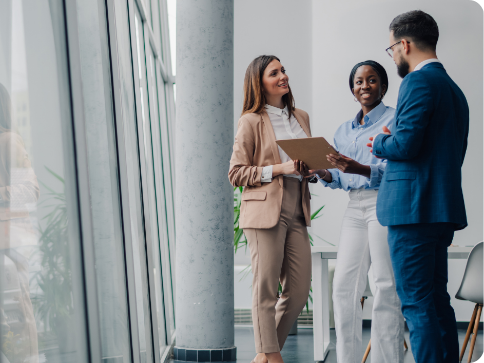 Three working professionals having a conversation with one woman holding a clip board.