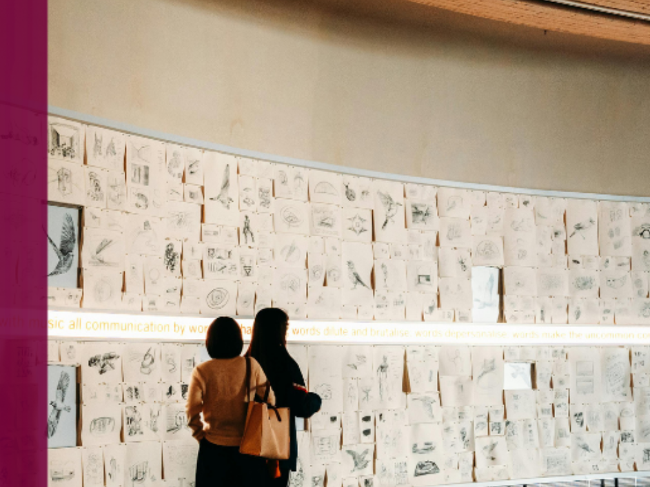Two people looking at illustrations posted along a wall